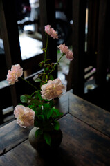 Vase of light chiffon pink rose vase on a wooden table