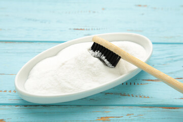 Toothbrush and baking soda to clean on blue background.