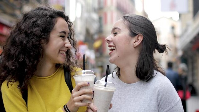 Two happy girls in Madrid drinking a milkshake