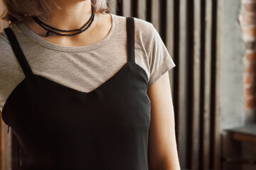 Woman wearing a black thin straps top over a gray T-shirt. Concept: Combination of clothes from the...