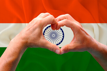 close-up of male hands in heart form against background of silk national flag of India, patriots of...