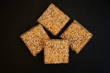 Til chikki on black textured background. Til chikki is an Indian sweets dishes made with jaggery and sesame. Indian festival makar sankranti special sweet.