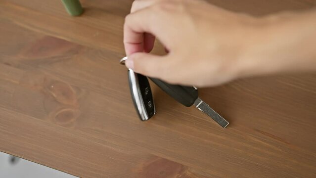 A person's hand reaches for car keys on a wooden table in a home interior setting.