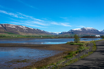 Icelandic landscape with a road in the foreground and snow-capped mountains in the background