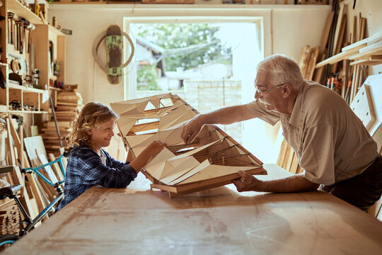 Grandfather and grandson building a wooden model in a workshop