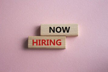 Now Hiring symbol. Concept word Now Hiring on wooden blocks. Beautiful pink background. Business and Now Hiring concept. Copy space