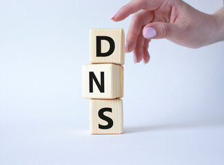 DNS -Domain Name Server - Consumer Price Index symbol. Concept word DNS on wooden cubes. Businessman hand. Beautiful white background. Business and DNS concept. Copy space.