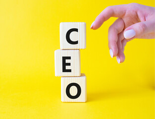 CEO - Chief executive officer symbol. Concept word CEO on wooden cubes. Businessman hand. Beautiful yellow background. Business and CEO concept. Copy space.