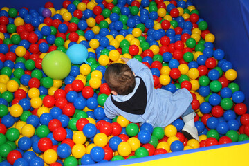 A child plays in a playpen with colored balls in a kindergarten