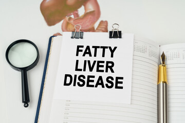 On the table there is a magnifying glass and a notepad with the inscription - Fatty liver disease