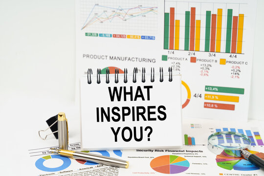 On the table are reports with graphs and a notepad with the inscription - WHAT INSPIRES YOU