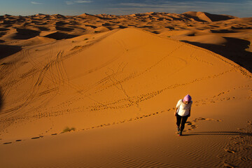 young woman walking on the dunes of the sahara desert