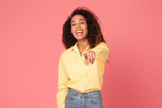 Happy black woman points at camera, choosing you on pink background