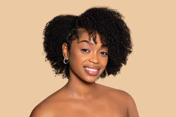 Smiling black woman with natural curly hair on beige background