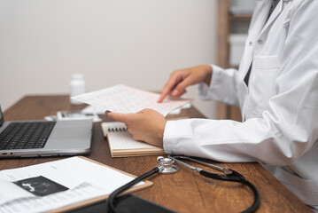 Young doctor reads papers with results of patient tests female cardiologist examines documents...