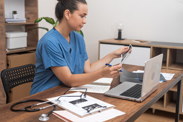 Ultrasound Analysis: A female doctor in blue scrubs intently analyzes ultrasound images of a...