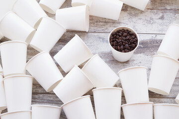 Coffee beans in a paper cup among empty cups.