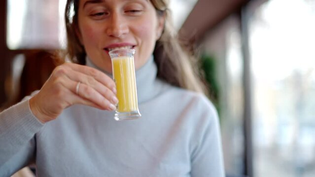 Woman drinking vitamin ginger immunity shot in a restaurant