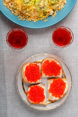 Sandwiches with red caviar and two glasses of wine on the table