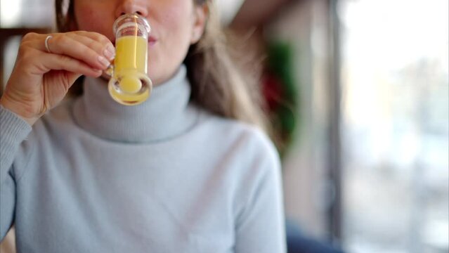 Woman drinking vitamin ginger immunity shot in a restaurant