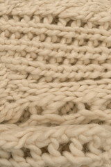 Fototapeta na wymiar A fragment of beige knitted fabric, knitted from white sheep wool.