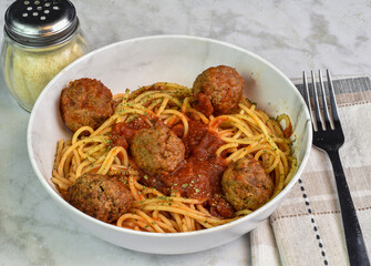spaghetti  in a bowl top with sauce and meat balls