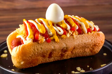 Hot Dog Colombian Grilled with Yellow Mustard and Ketchup, minimal close up. Hot dog freshly baked on plate, homemade. Grocery product advertising, menu or package, selective focus.