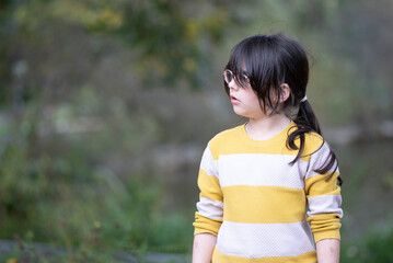 Fototapeta premium Portrait of a cute little girl in the park, shallow depth of field