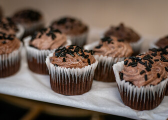 Delicious chocolate cupcakes with icing and sprinkles on a table