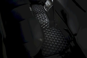 The second row of a modern car with a leather floor mat. The interior is luxurious and...