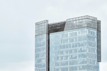 High-rise office building. A modern glass building stands tall against a cloudy sky showcasing architectural brilliance and urban development.