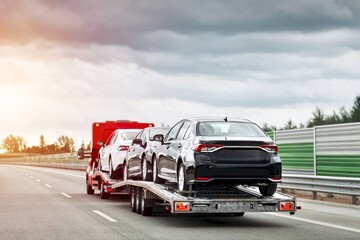 A rollback tow truck transports a broken car on the public road. Car failure during the journey....