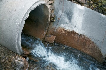 The river is polluted by industrial waste from a drainpipe that dumps sewage into the water,...