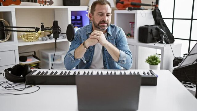 A middle-aged man plays a keyboard in a modern home music studio, conveying creativity and professionalism.