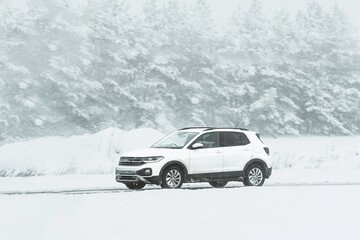 Car on a winter road. Dangerous driving conditions on the highway. Winter tires and undercarriage rust and corrosion concept. Slippery highway.