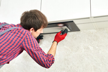 Mans hands removing a filter from cooker hood for cleaning or service. Replacing filter in kitchen...