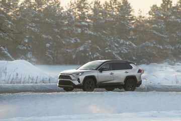 A white SUV conquers a snowy landscape showcasing winter driving. The vehicle’s motion is...