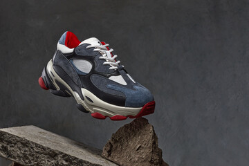 Sneakers on dark gray concrete background. Texture of the old dark stone or broken brick. The...