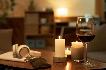 Background image of candles and glass of wine on wooden table in cozy home set for relaxing evening copy space