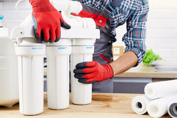 Plumber installs or change water filter. Replacement aqua filter. Repairman installing water filter...