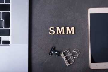 Abbreviation SMM made with wooden letters and phone, laptop. Social Media Marketing concept