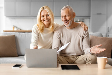 Happy mature man and woman paying bills online