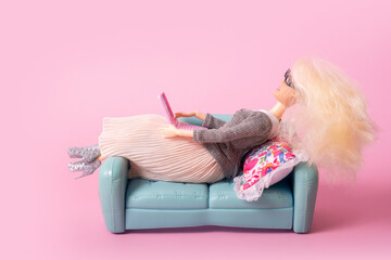 Doll with laptop on sofa. Working or relax at home, freelance creative concept.