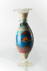 Glass bottle with colorful sand on a white background