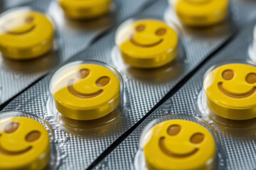 Smiling yellow pills in blister pack closeup. Selective focus.