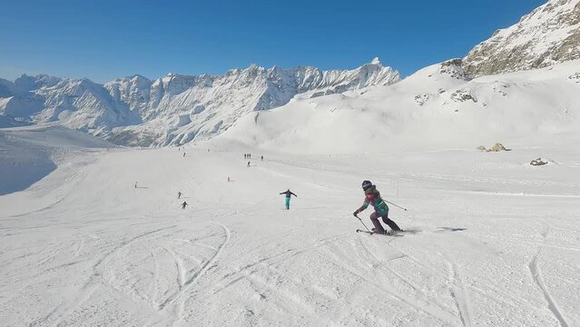 Follow woman skiing downhill on a ski slope in Cervinia ski resort, Italy
