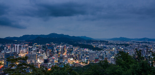 Seoul, South Korea cityscape during a dusk with mountains in a background.