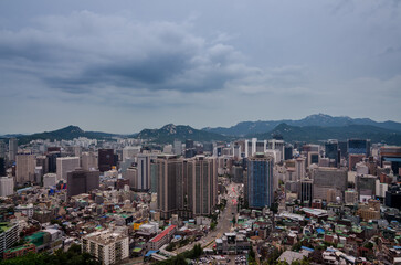 Seoul, South Korea cityscape during a dusk with mountains in a background.