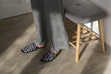 Woman wearing grey home slippers and standing on hardwood flooring in apartment