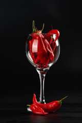 Peppers, beautiful red peppers in detail inside a cup, black background, selective focus.